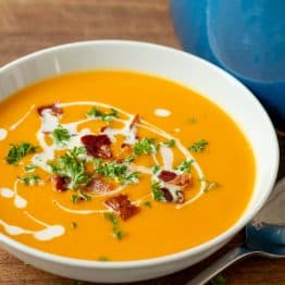Creamy sweet potato soup in bowl garnished with coconut milk