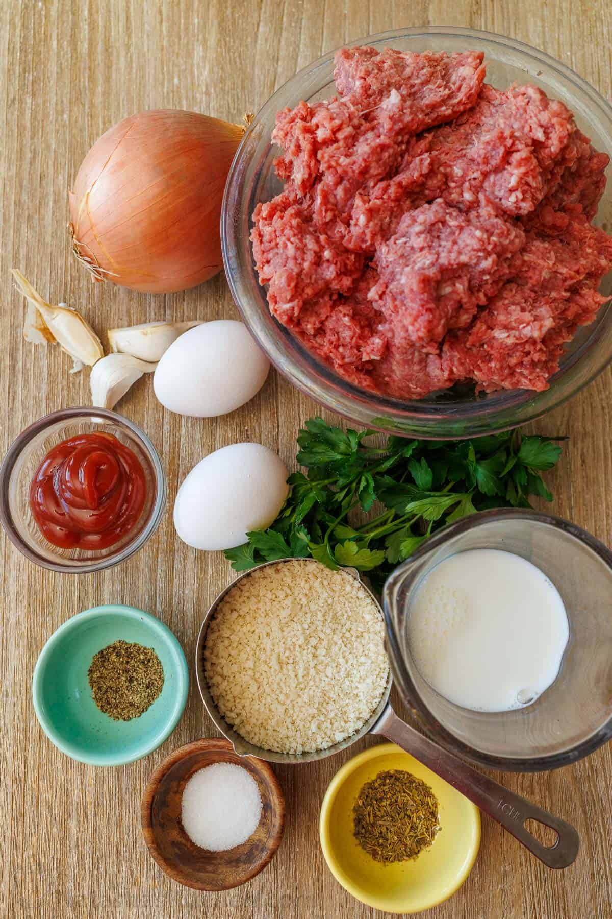 Meatloaf Recipe Ingredients with ground beef, bread crumbs, onion, egg, milk, ketchup and seasonings.
