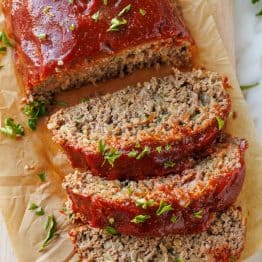 Juicy sliced meatloaf on a cutting board garnished with parsley