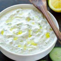 Tzatziki sauce served in white bowl with spoon